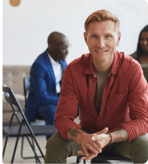 man in red shirt sitting in front of group