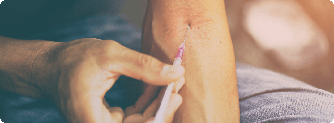 man pushing needle against his arm