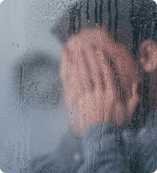 man holding his face behind fogged window